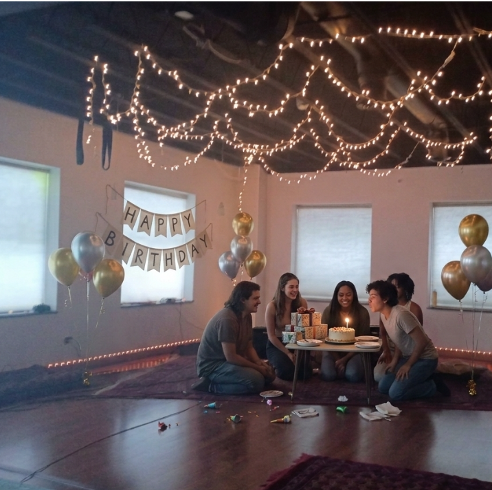 Birthday celebration at Art Hall with string lights, balloons, and guests around a cake